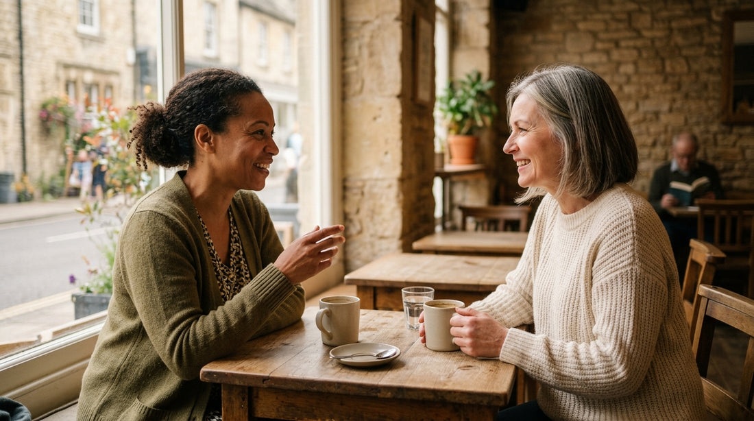 Two women at a coffee shop table having a calm morning conversation with drinks