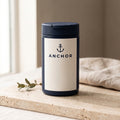 Anchor Creatine Monohydrate navy tub on travertine stone with eucalyptus, natural window light