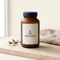 Anchor Complete Multivitamin navy tub on travertine stone with eucalyptus, natural window light